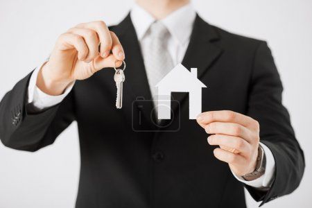 房地产经纪人家的钥匙给人与签署协议与房子模型, 计算器协议在办公室